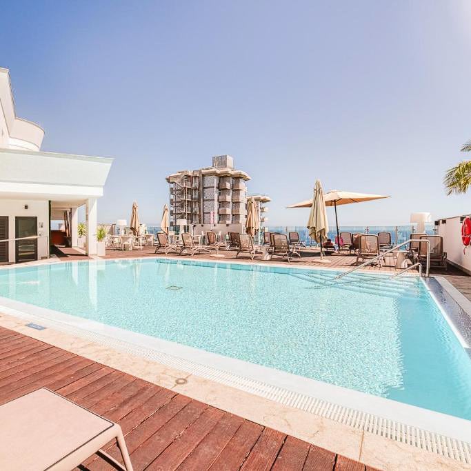 a swimming pool with chairs and umbrellas in Vila Baleira in Funchal Madeira