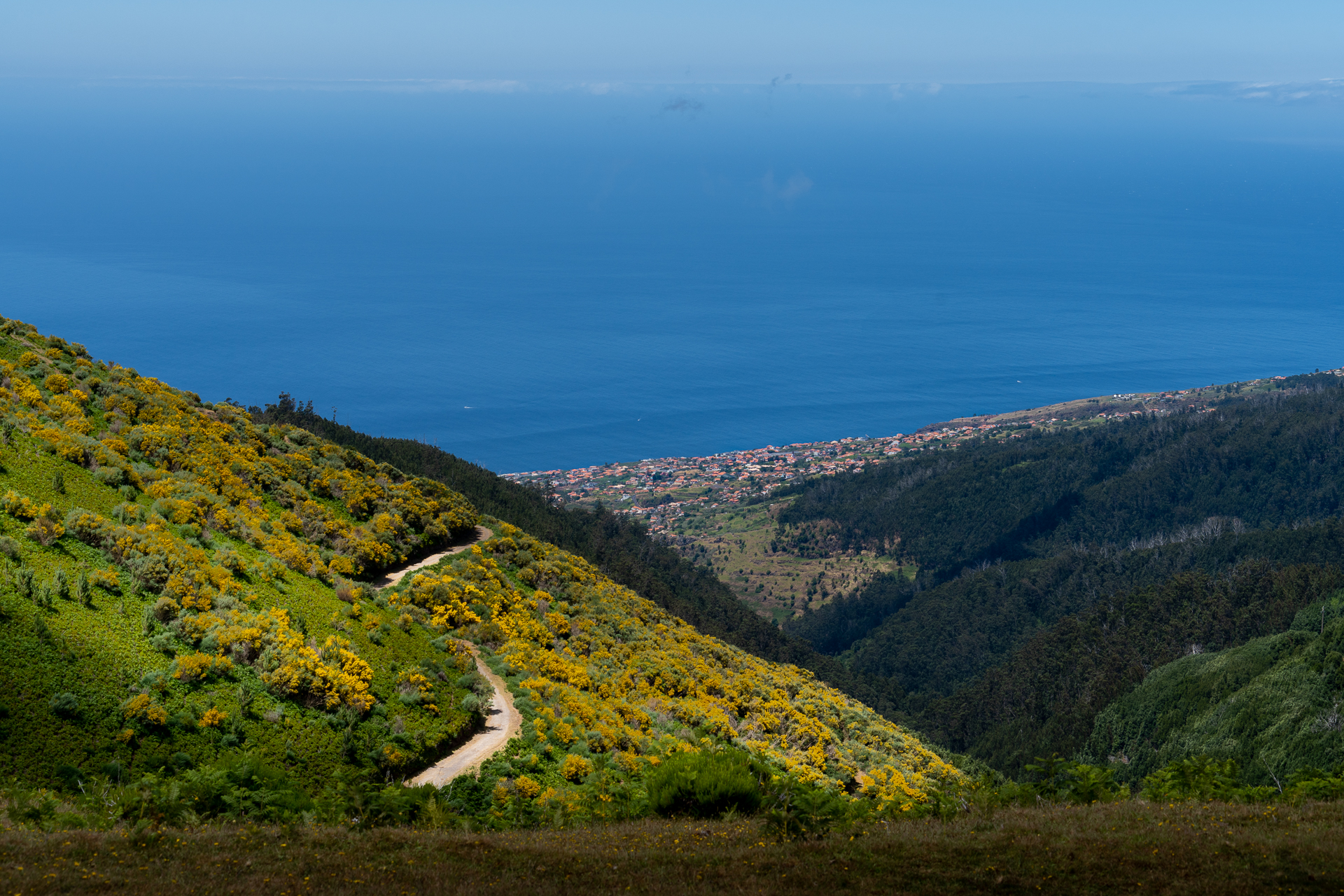 a dirt road on a hill with a city in the background renting a car in Madeira